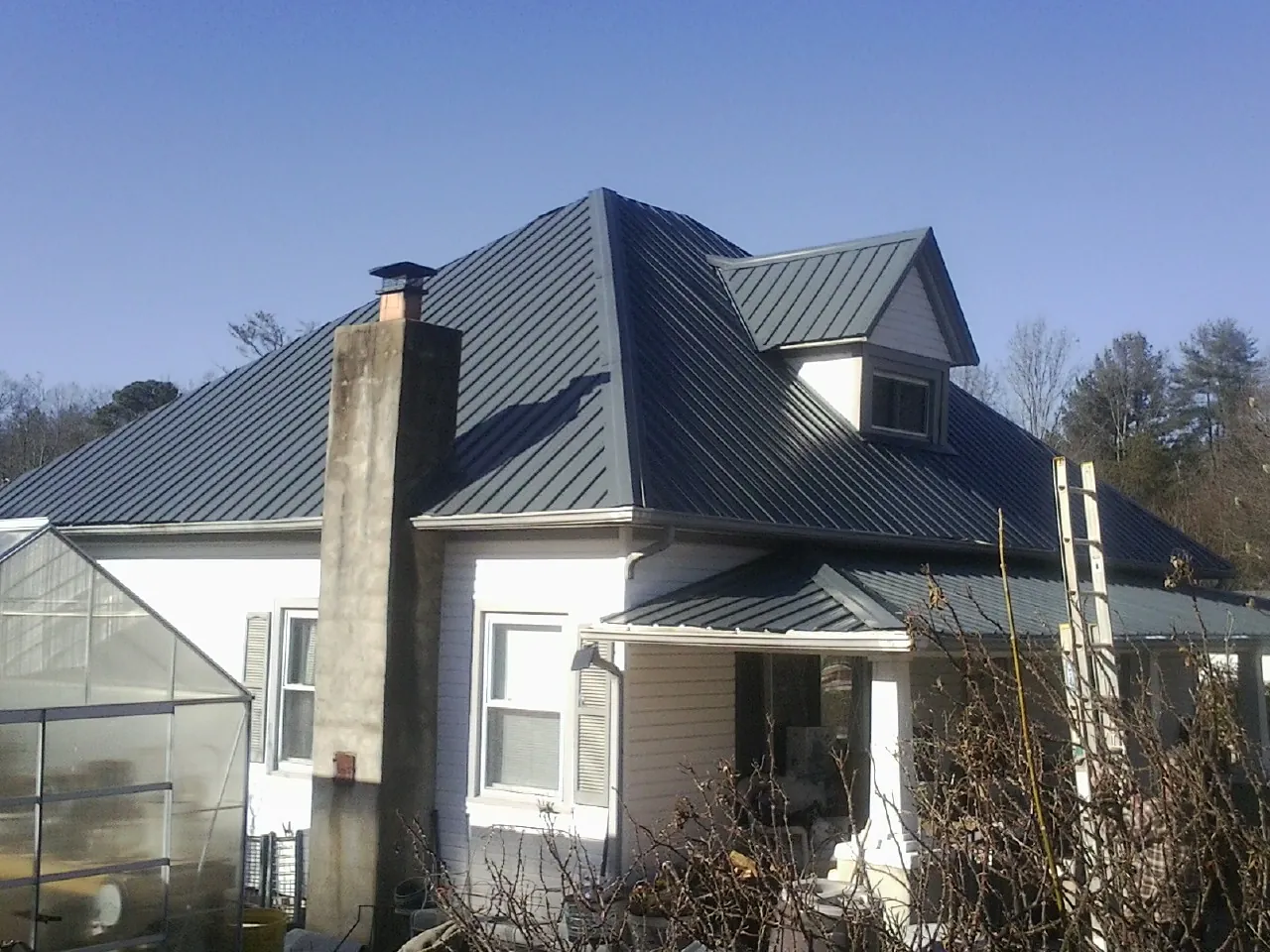Dark blue standing seam metal roof on a white farmhouse with dormer — Slate & Tile Roof Repair by Roofing Brothers in Rocky Top