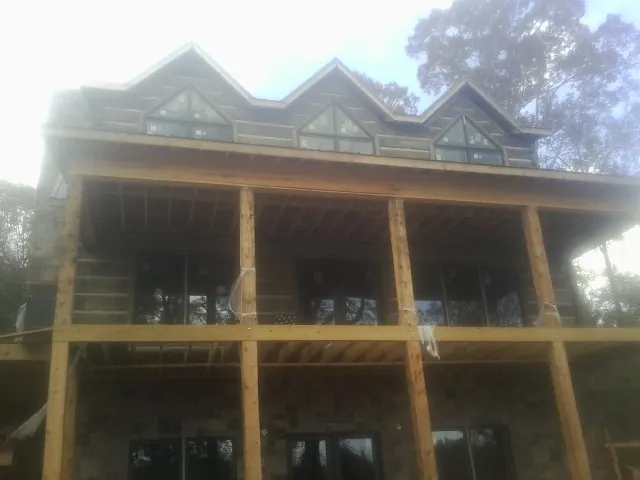 Dormers and porch framing on a large log home under construction — Roof Coating work by our crew in Rocky Top