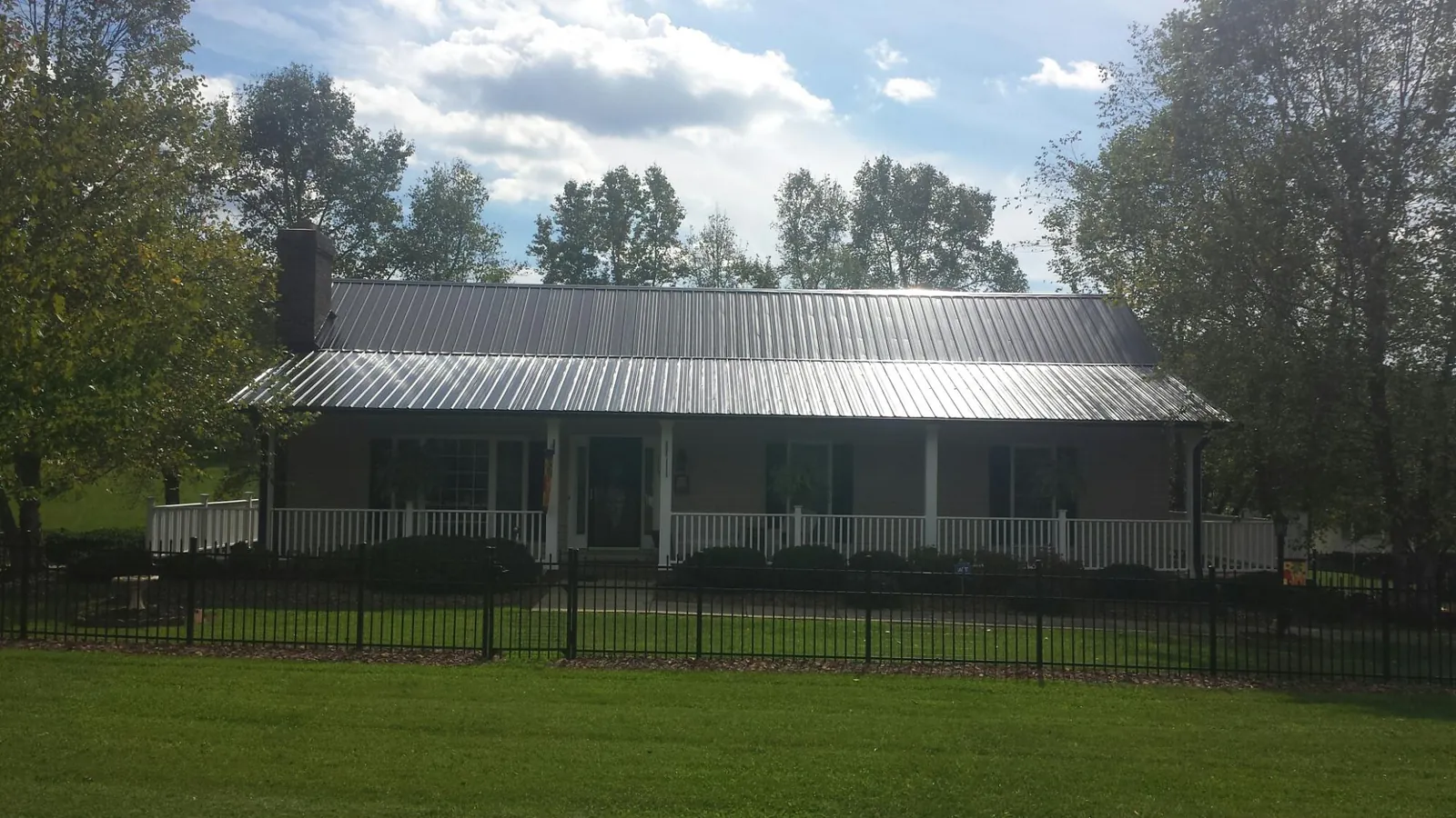 Gray metal roof on a brick ranch with a full width front porch — Gutter Guard Installation work by our crew in Rocky Top