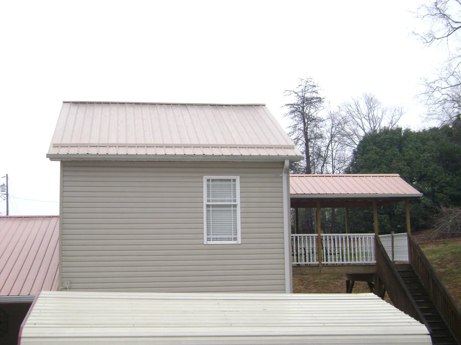 Tan metal roofs on a two story addition and attached porch, from a Roof Replacement job in Rocky Top