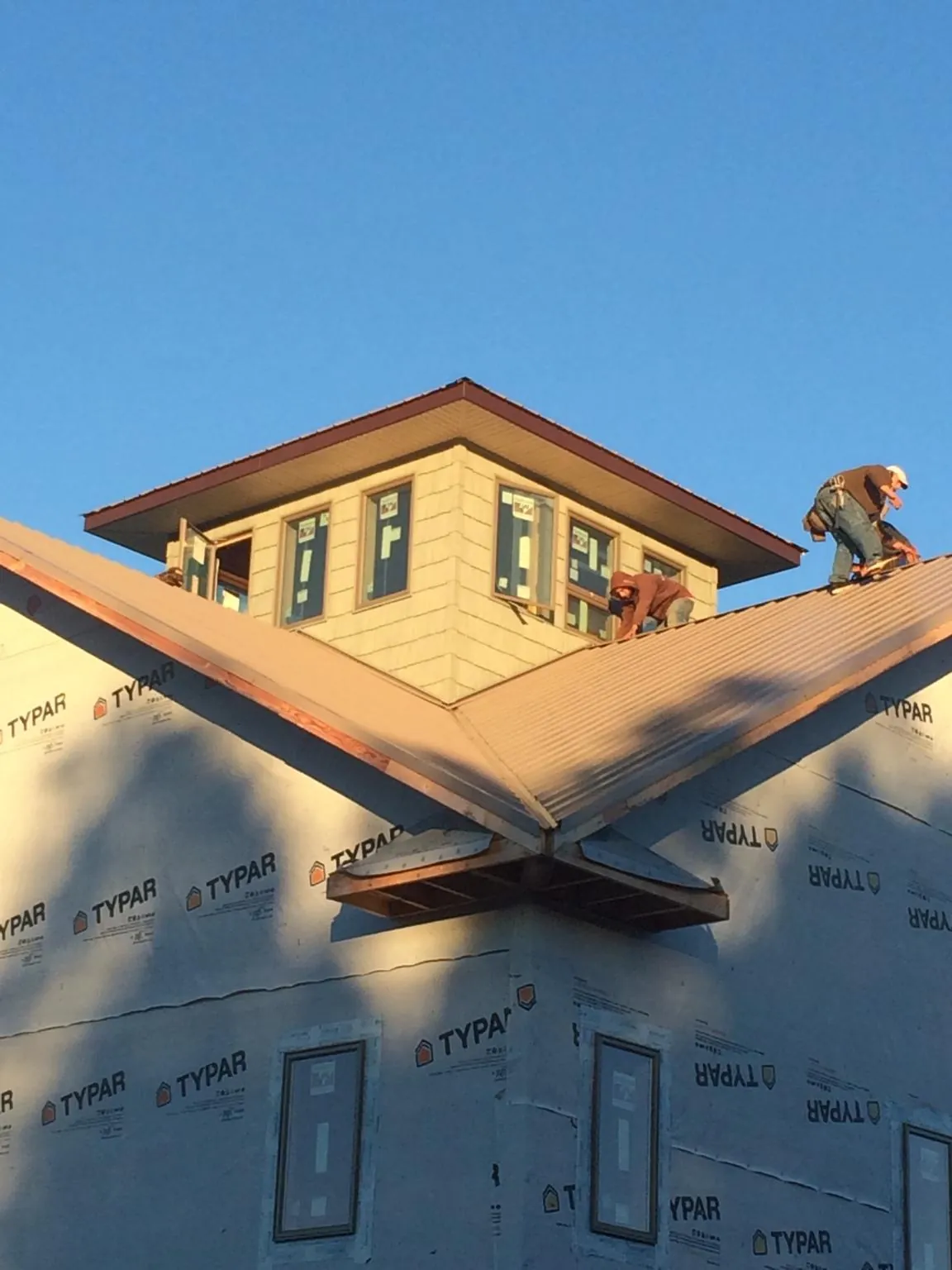 Roofers working around a rooftop cupola on a new metal roof at sunset — Roof Waterproofing in Rocky Top by Roofing Brothers